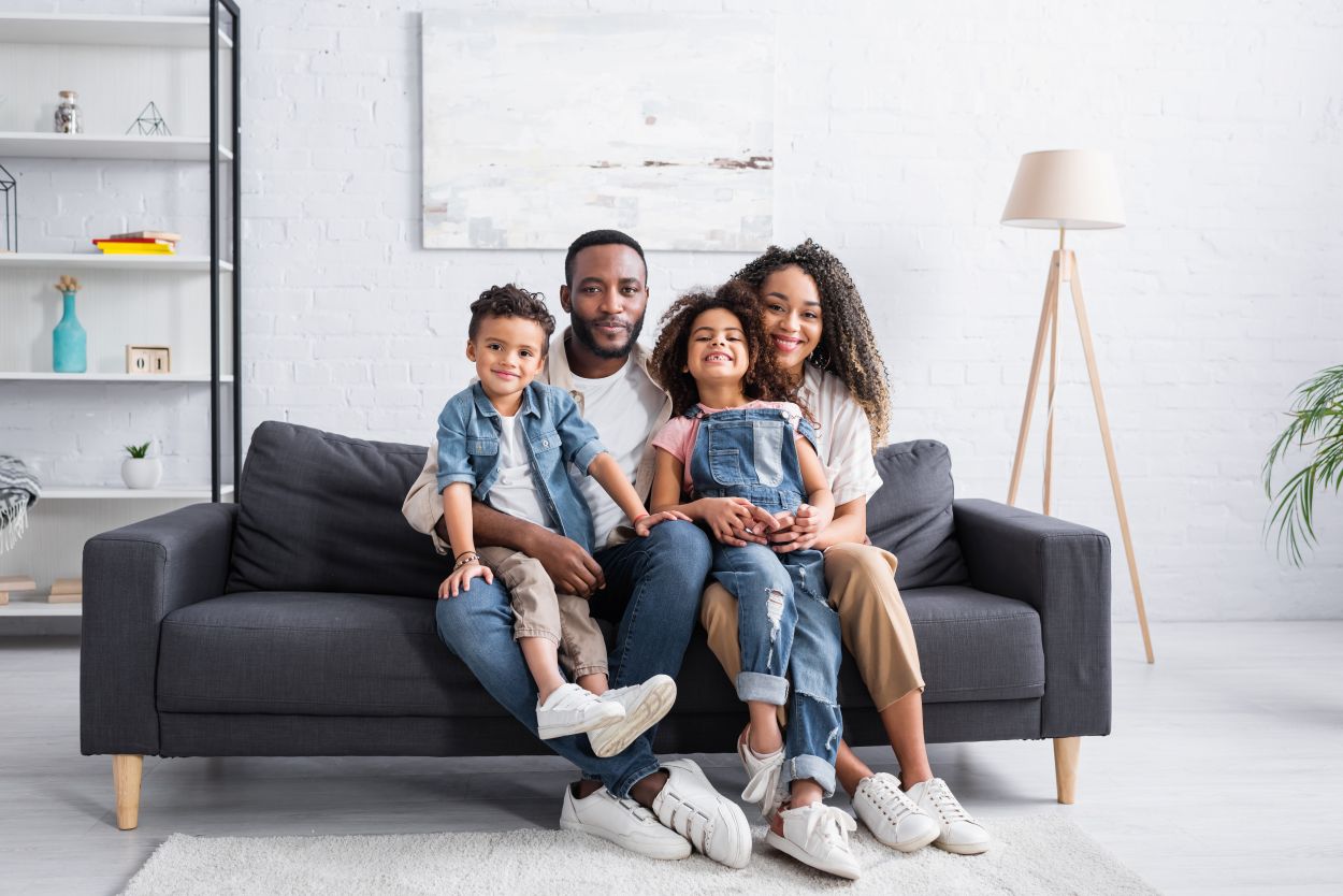 happy african american family sitting on sofa at home and looking at camera